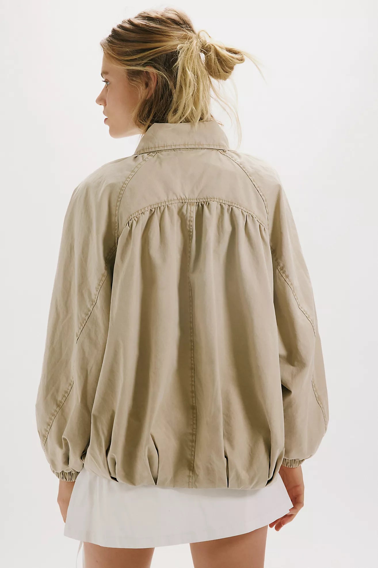 Person wearing a beige jacket on a white background