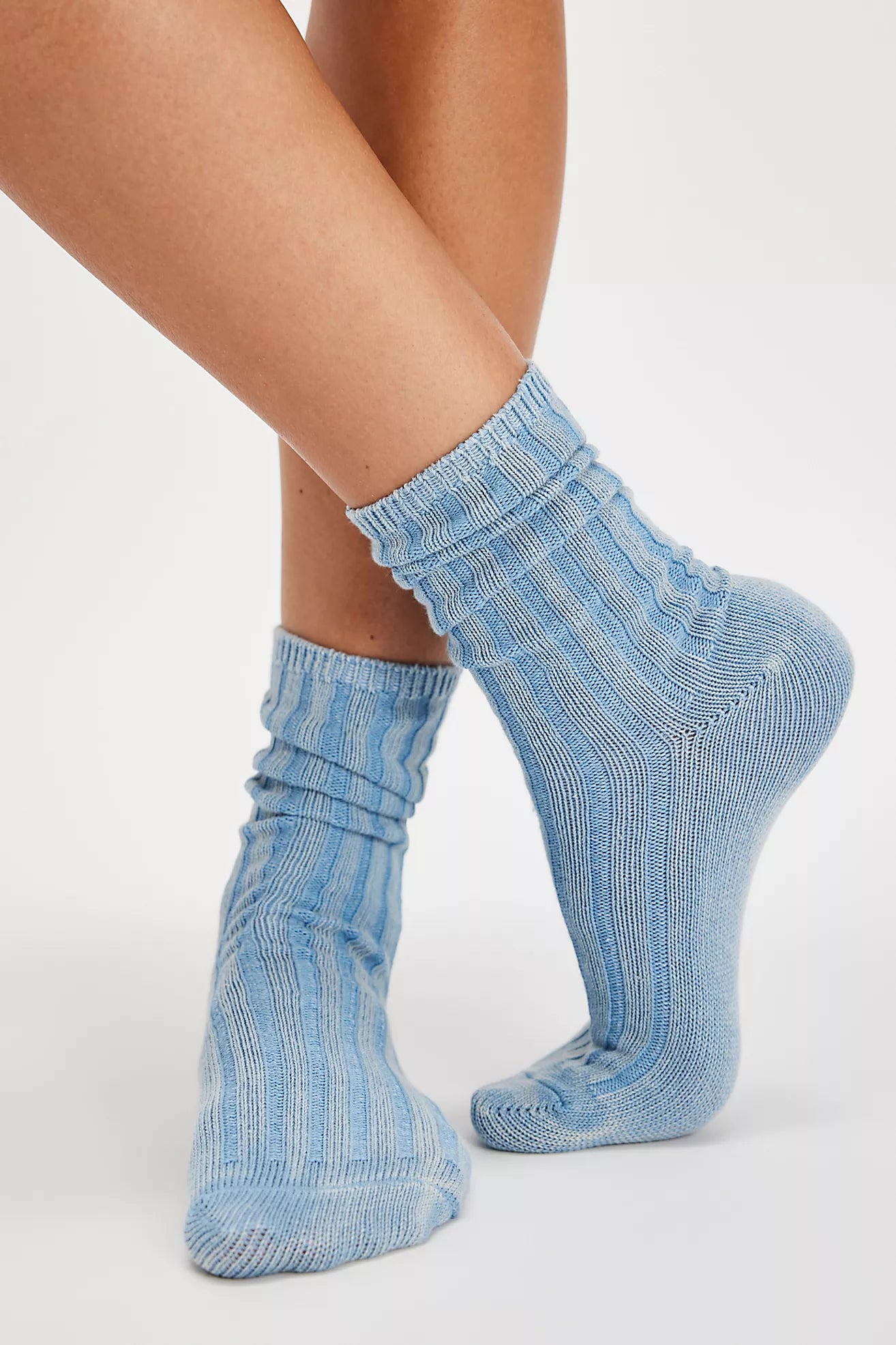 Light blue ribbed crew socks worn on a model's feet, shown against a plain light gray studio background.
