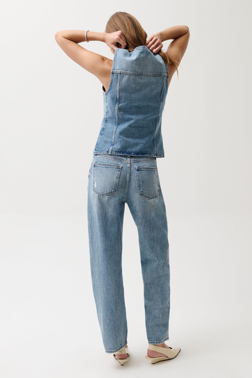 Person wearing a denim jumpsuit on a white background
