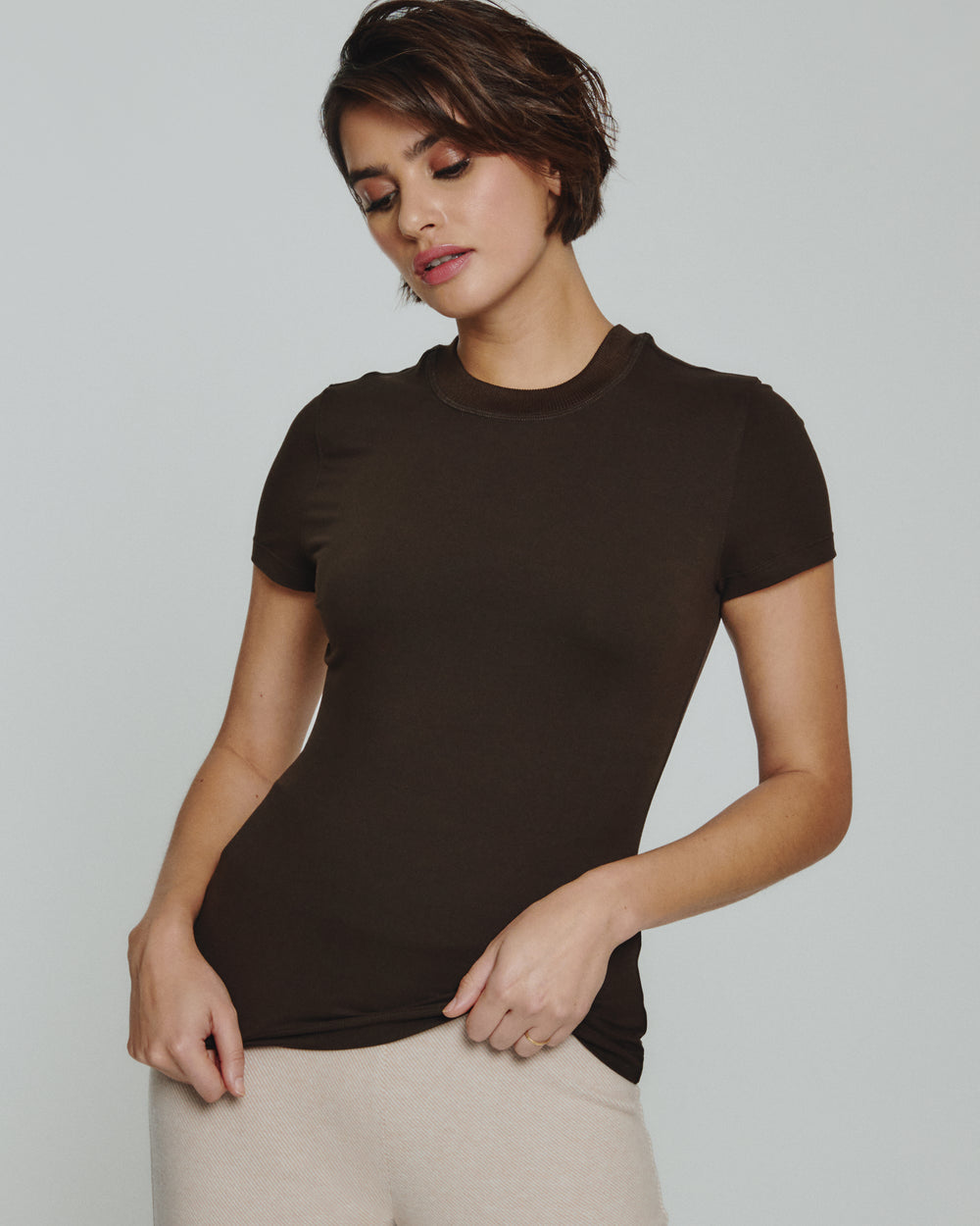 Woman wearing a brown t-shirt against a plain background