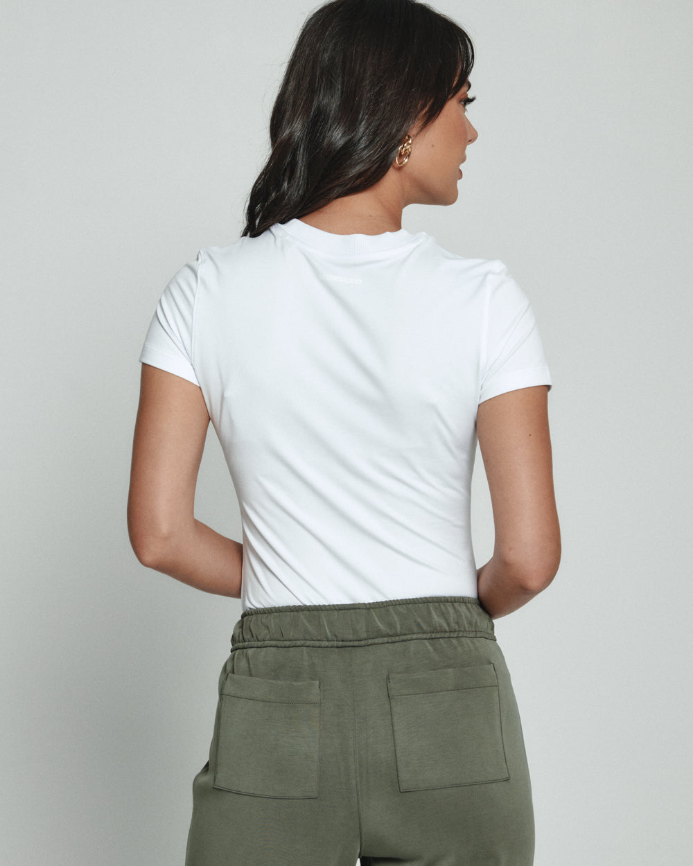 Person wearing a white top and green pants against a plain background