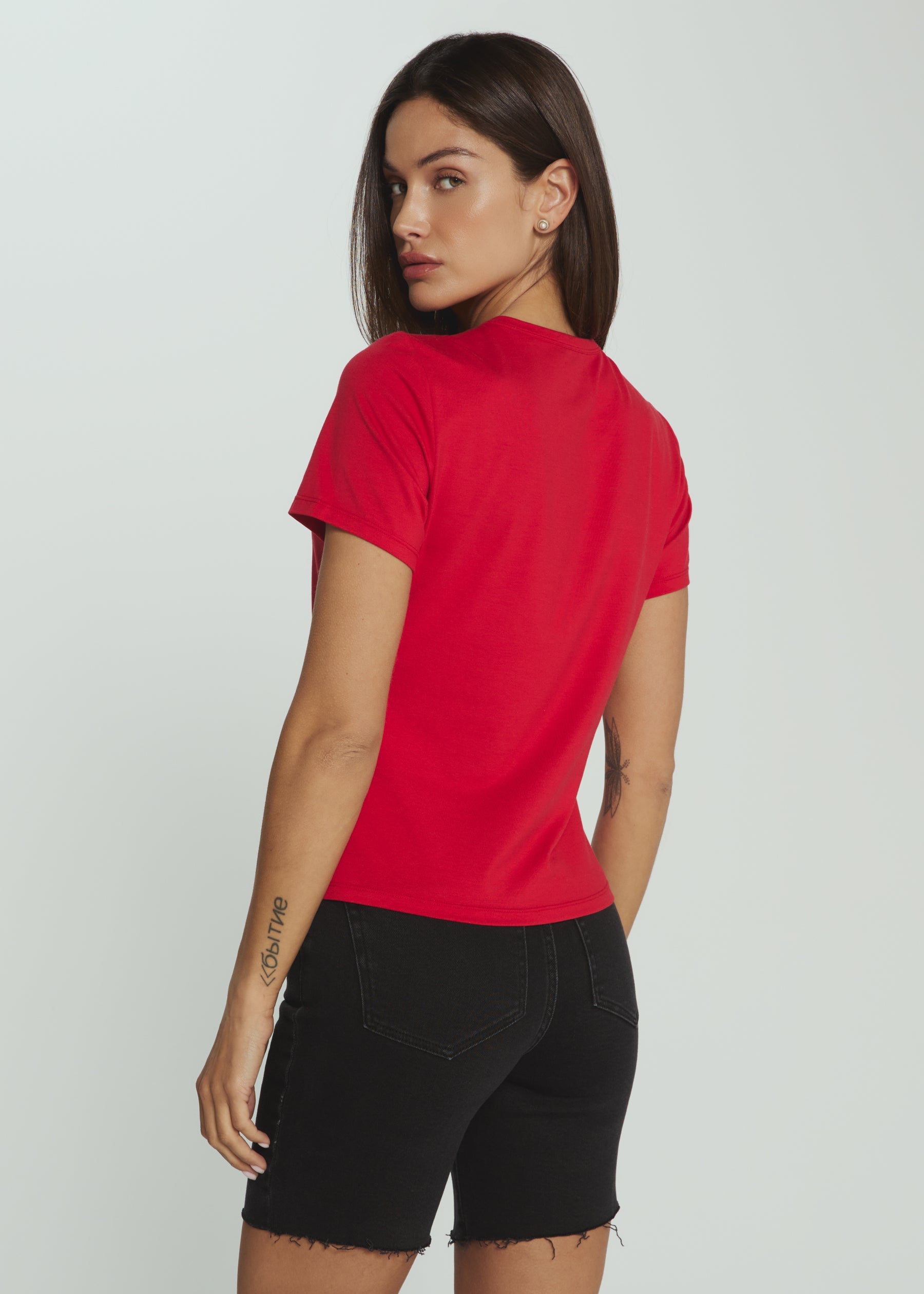 Woman wearing a red t-shirt and black shorts on a plain background