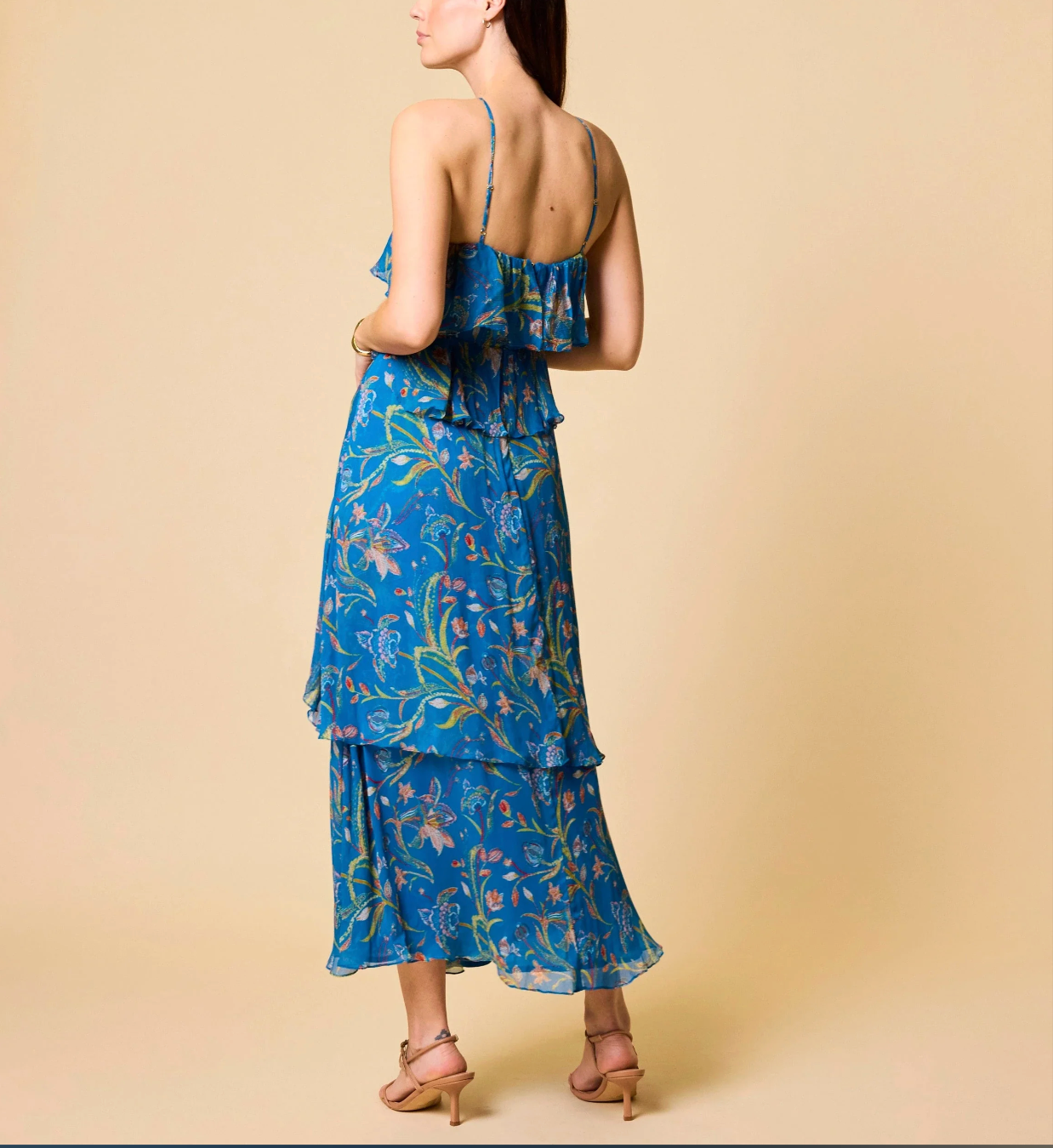Woman wearing a blue floral dress against a beige background