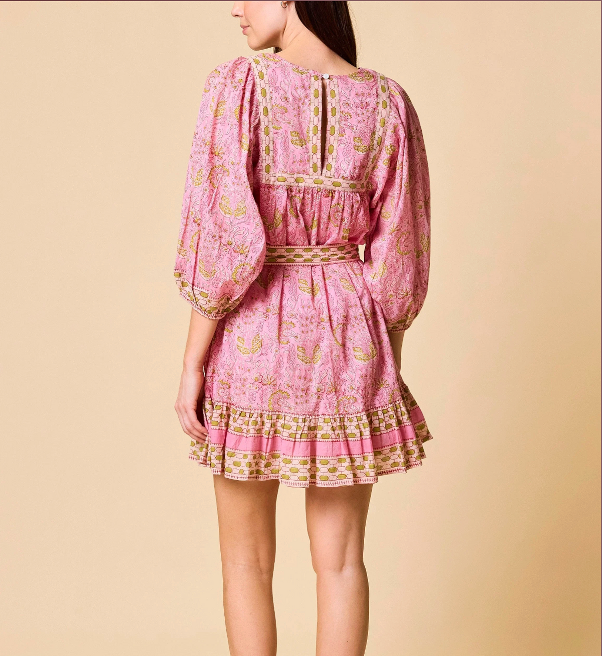 Pink dress with gold patterns on a beige background