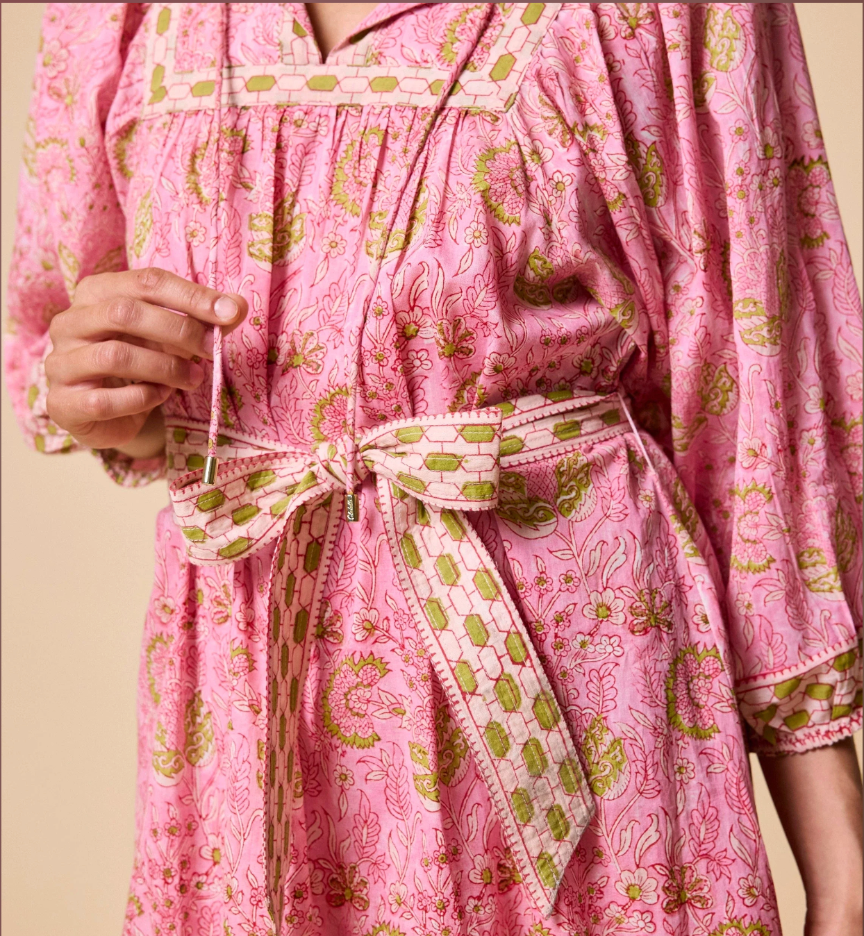 Pink robe with green floral pattern on a beige background
