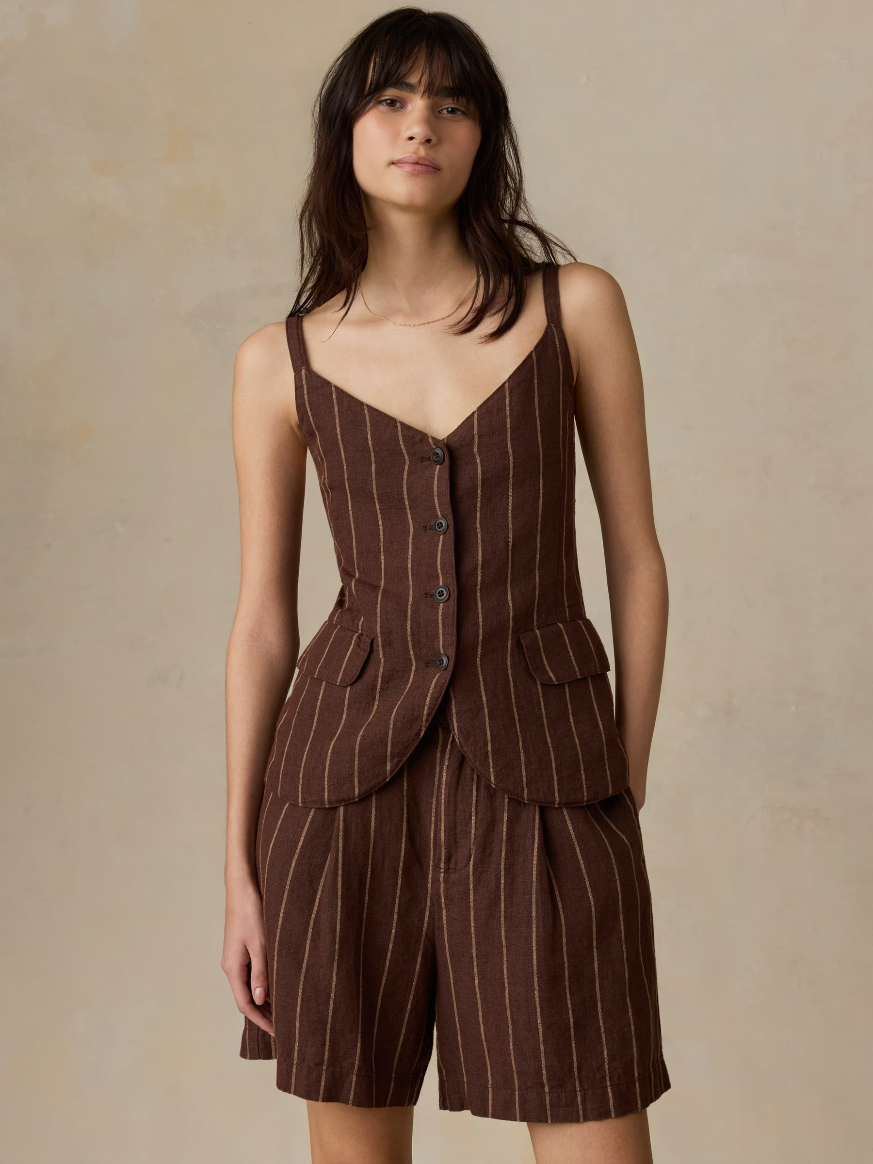 Woman wearing a brown pinstripe dress against a beige background