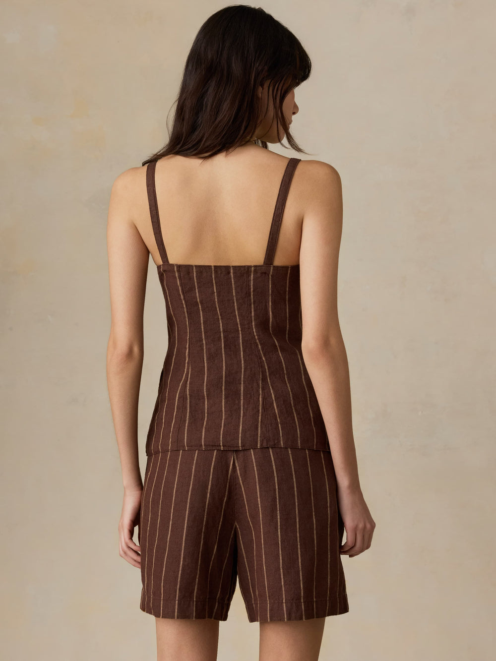 Woman wearing a brown pinstripe romper against a beige background