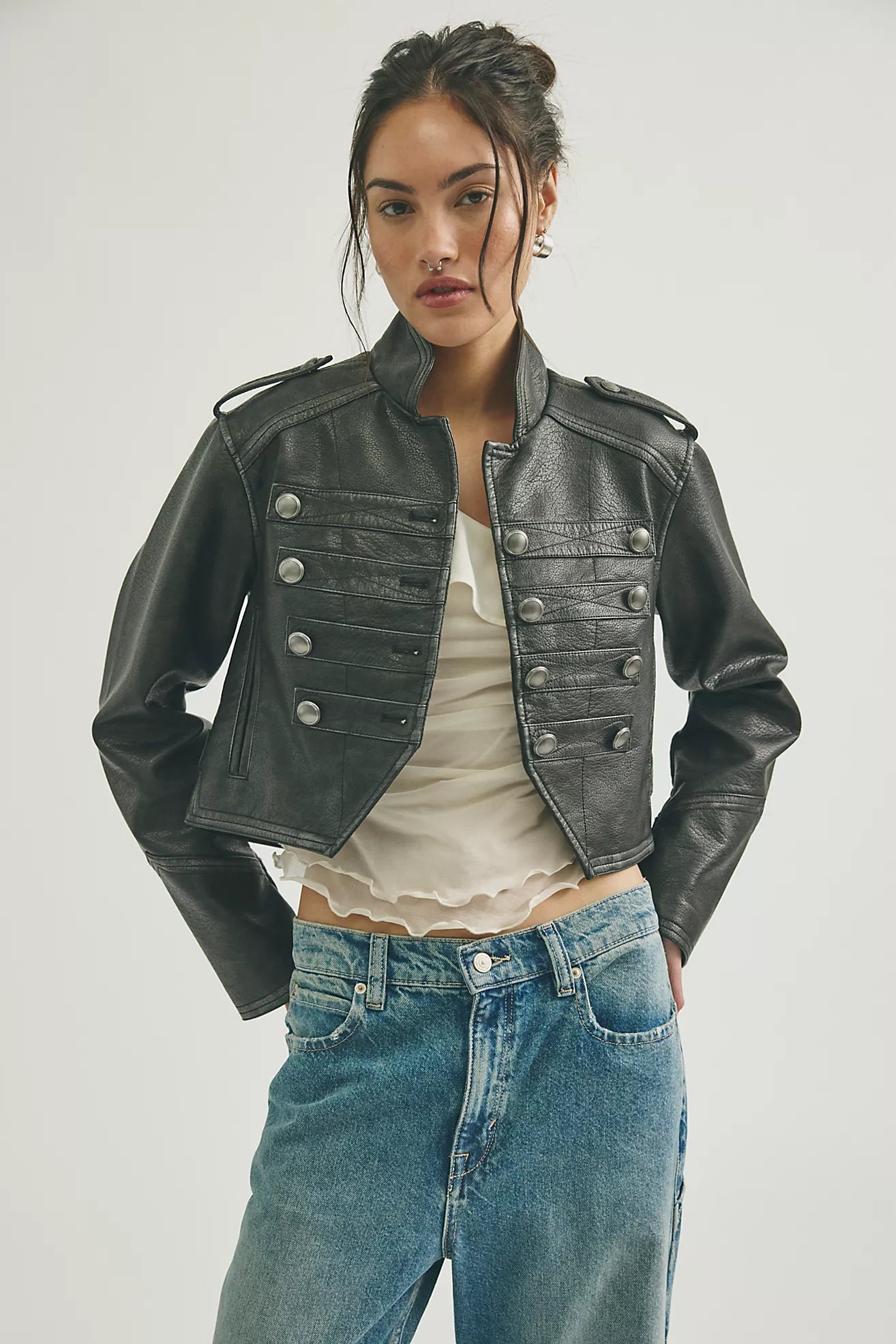 Woman wearing a black leather jacket and blue jeans on a white background