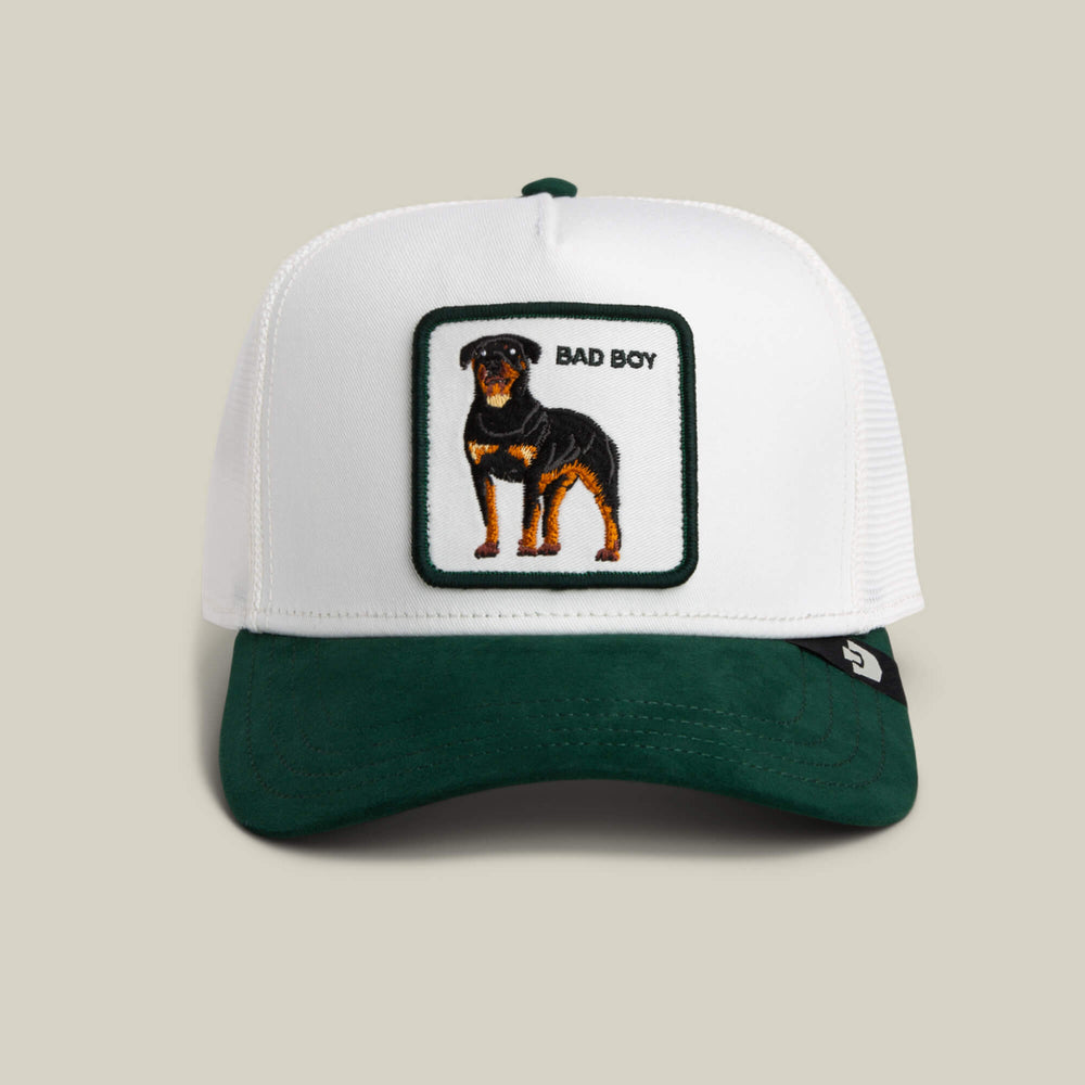 White and green cap with a dog illustration and 'Bad Boy' text on a beige background