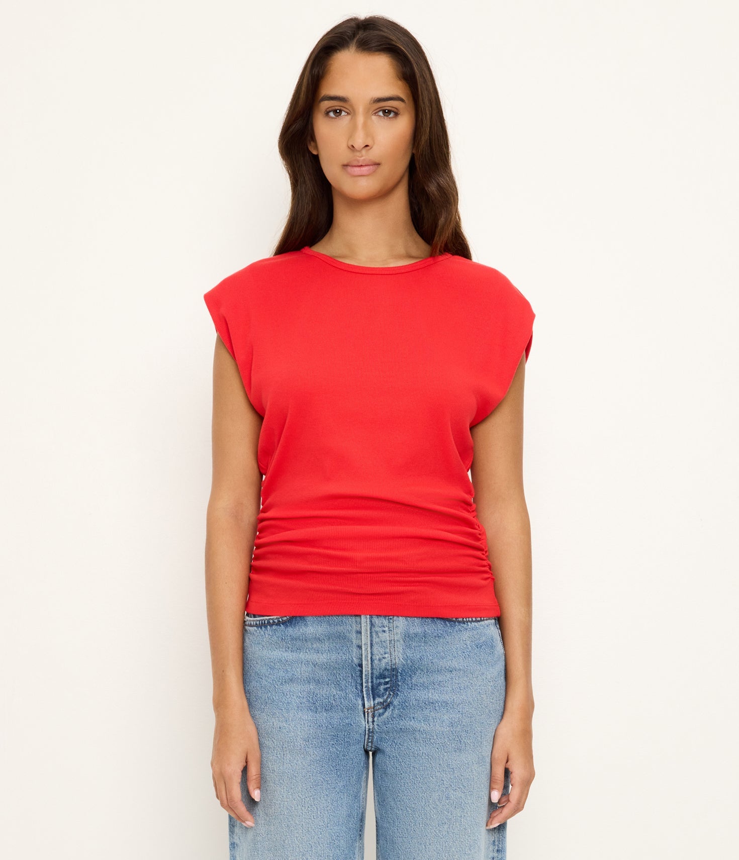 Woman wearing a red top and blue jeans on a white background