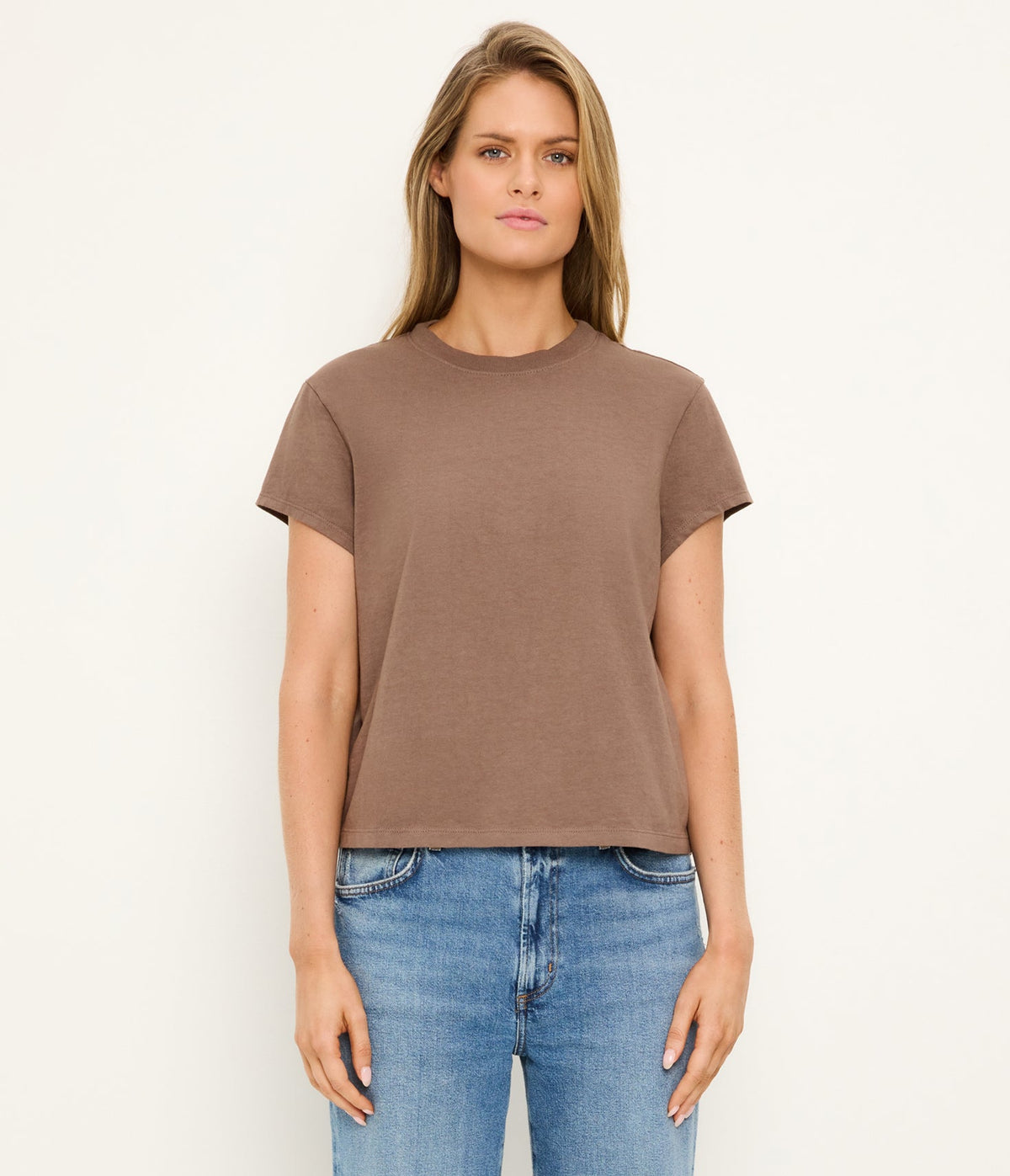 Woman wearing a brown t-shirt and blue jeans on a white background