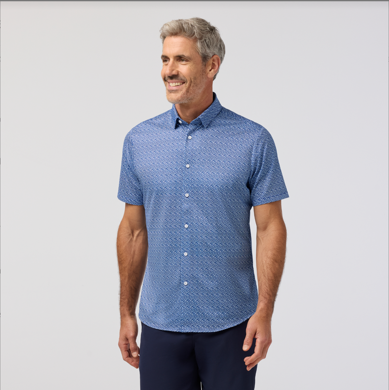 Man wearing a blue patterned shirt against a light gray background