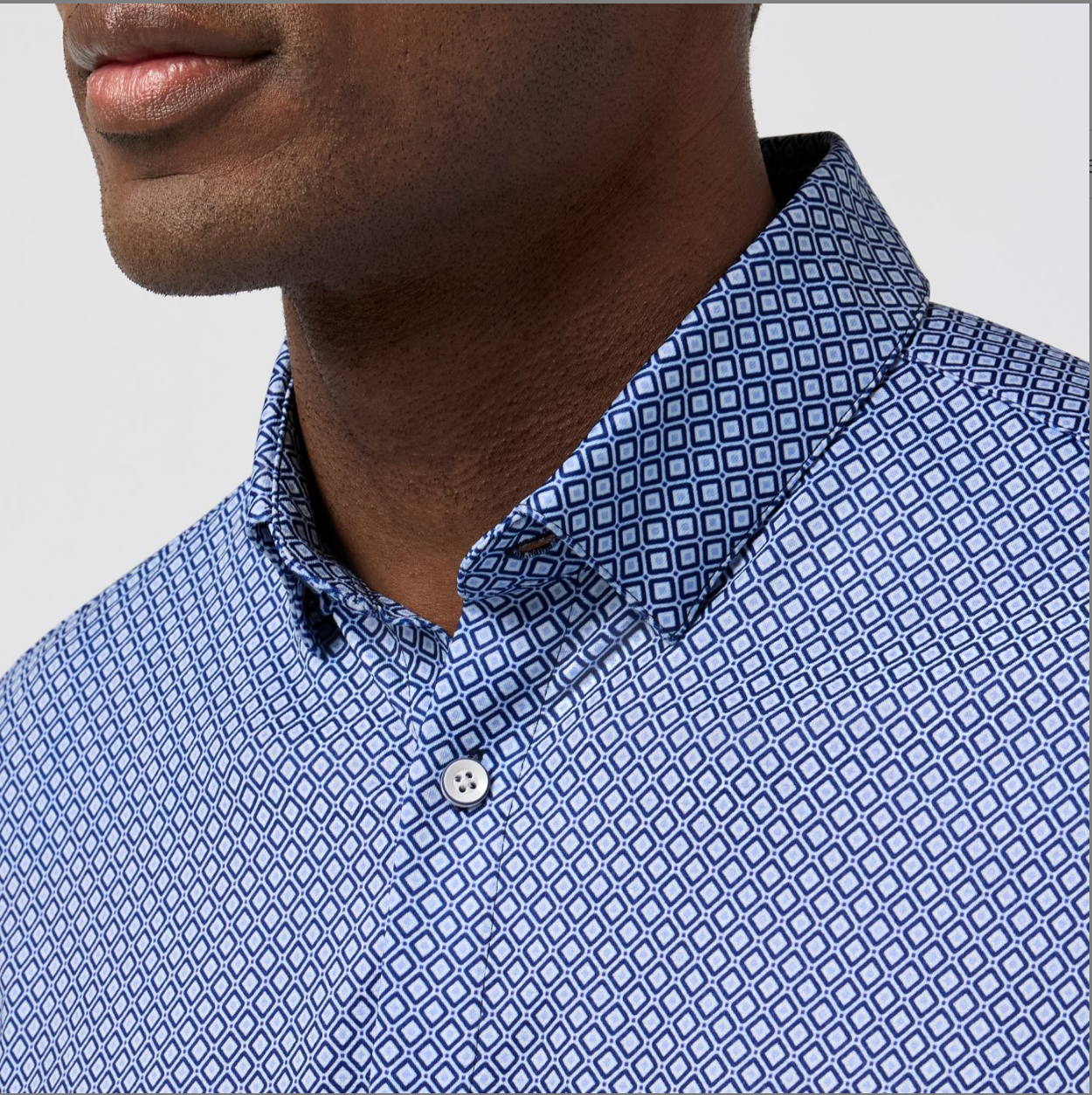 Close-up of a person wearing a blue patterned shirt with a white background