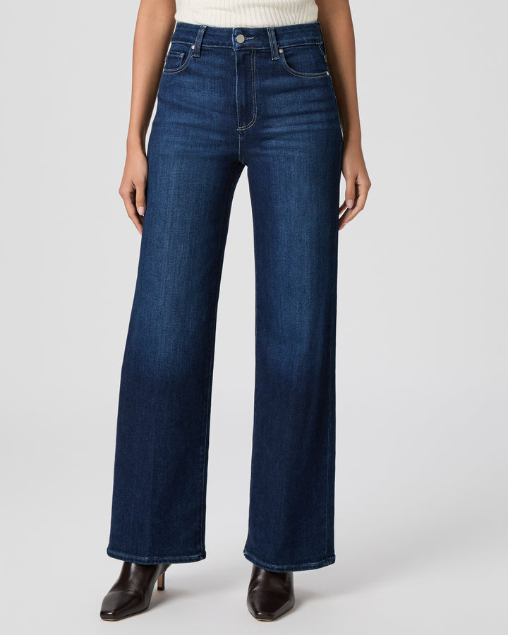 Person wearing dark blue wide-leg jeans on a light gray background