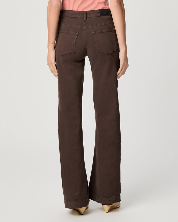 A model shown from the back wearing dark brown wide-leg jeans, a pink ribbed top, and gold pointed-toe heels against a light gray studio background.