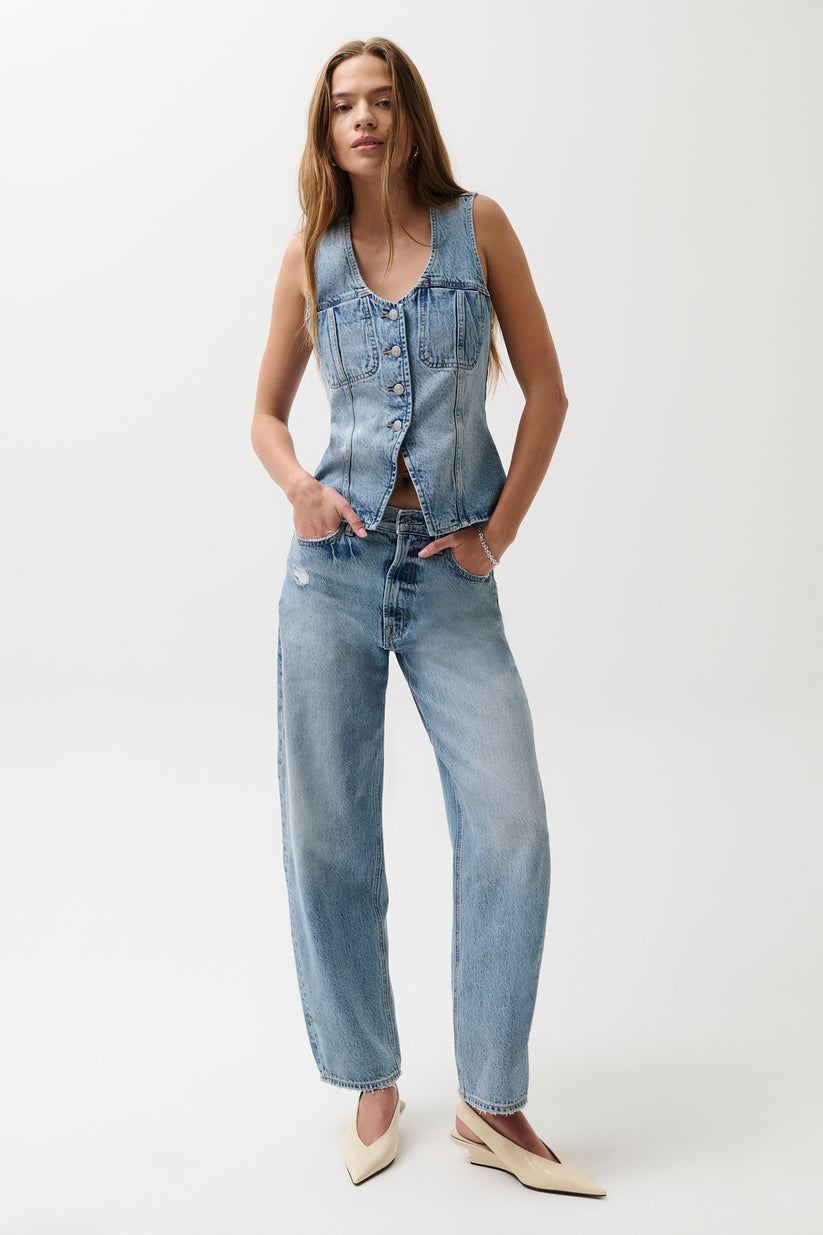 Woman wearing a denim vest and jeans on a white background