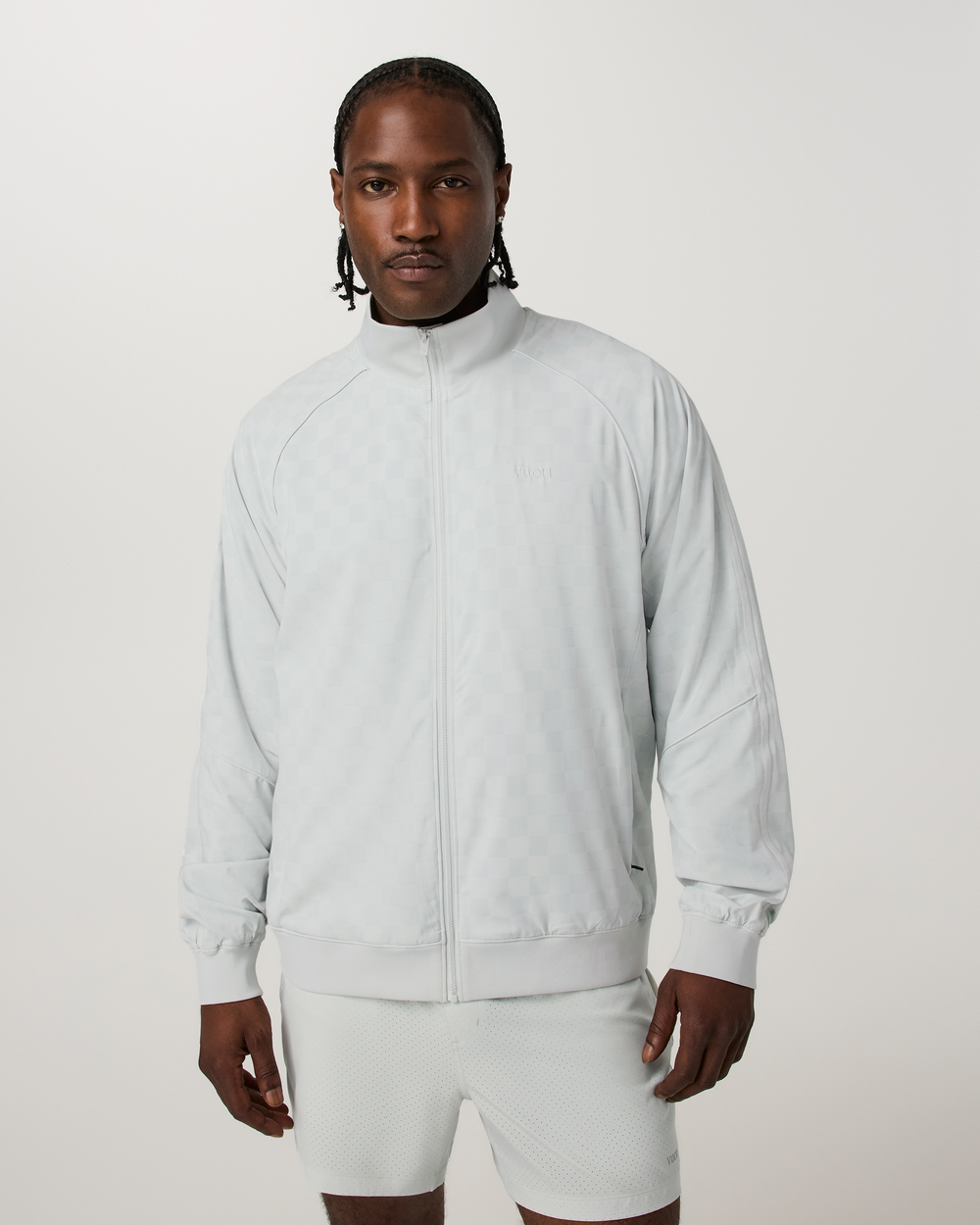 Man wearing a light gray tracksuit on a white background