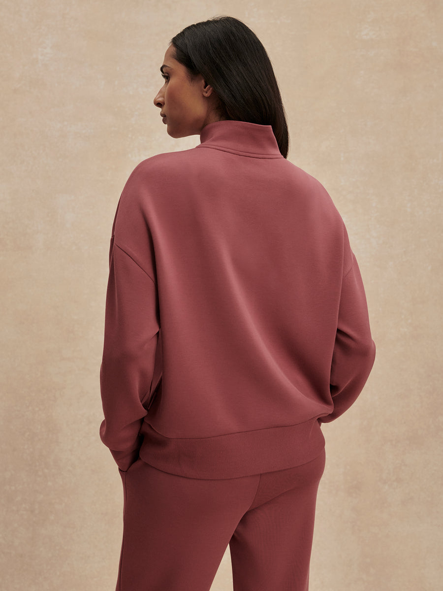 Person wearing a maroon tracksuit against a beige background
