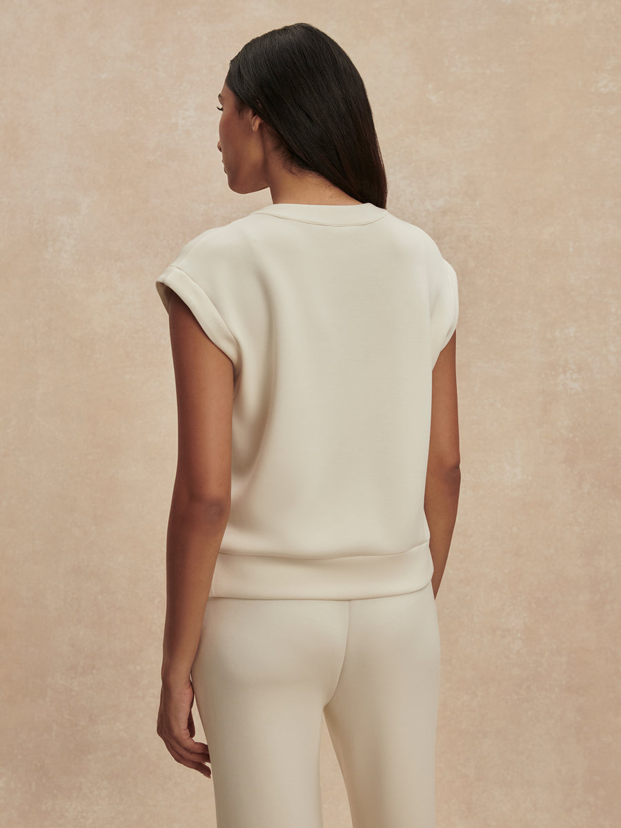 Woman wearing a cream-colored outfit against a beige background