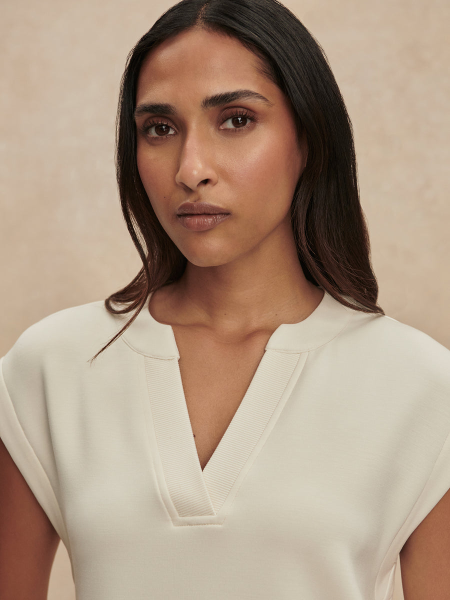 Woman wearing a white blouse against a beige background